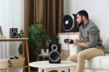 Parlak odadaki modern ses hoparlörlerini uzaktan kontrol eden adam