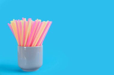 Açık mavi arkaplanda renkli plastik pipetler, metin için boşluk