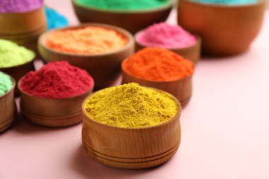 Pembe arka planda ahşap kaselerde renkli tozlar. Holi festivali kutlaması