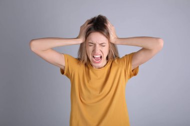 Gri arka planda stresli genç bir kadının portresi