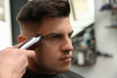 Profesyonel berber kuaförde şık saç kesimi yapıyor, yakın plan.