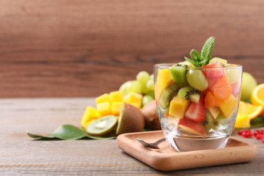 Lezzetli taze meyve salatası ahşap masada, metin için yer var.