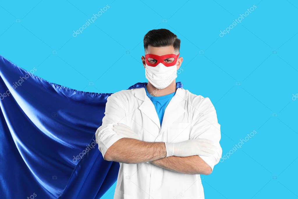 Doctor wearing face mask and cape on light blue background. Super hero power for medicine
