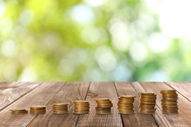 Bulanık arka plana karşı ahşap masaya para yığılmış. Yatırım kavramı