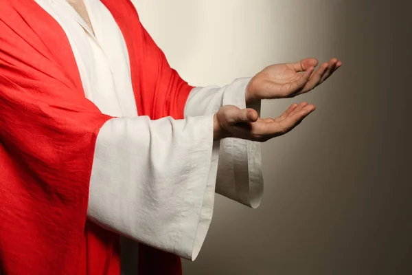 Jesus Christ reaching out his hands on beige background, closeup