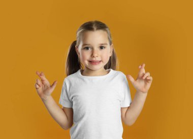 Sarı arka planda çapraz parmaklı çocuk. Batıl inanç kavramı