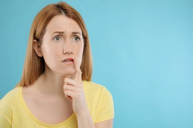 Açık mavi arka planda uçuktan muzdarip üzgün bir kadın. Metin için boşluk