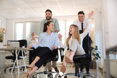 Mutlu ofis çalışanları iş yerinde sandalyeye biniyor.