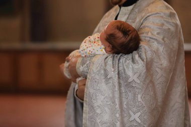 Papazlar vaftiz töreni sırasında kilisede çok tatlı bir bebeği kucağında tutuyorlar.