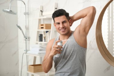 Banyoda koltuk altına deodorant süren yakışıklı bir adam, mesaj atmak için yer var.