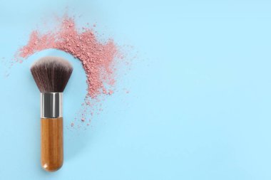 Makyaj fırçası ve dağınık allık açık mavi arka plan, üst manzara. Metin için boşluk