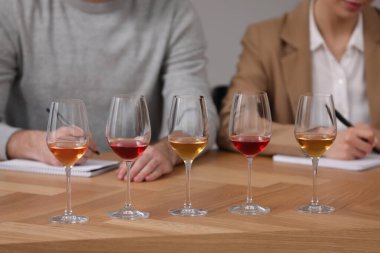Tadına bakmak için farklı türde şarap ve ahşap masadaki şarap garsonları, yakın plan.