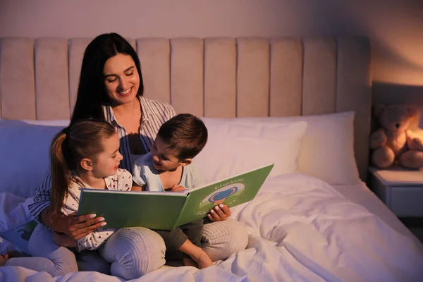 Mother reading bedtime story to her children at home