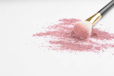 Hafif arka planda ezilmiş kozmetik ürünlerle makyaj fırçası. Metin için boşluk