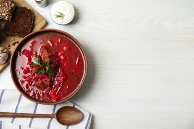Ukrayna borsch 'u ile süslü kahverengi kil kase beyaz ahşap masada, düz yerde servis edilir. Metin için boşluk