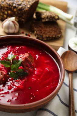 Ukrayna borsch 'u beyaz masada servis edilen şık kahverengi kase, yakın plan.