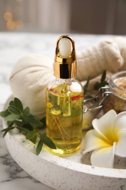 Beyaz mermer masa üzerinde gerekli yağ ve plumeria çiçeğiyle güzel bir spa kompozisyonu, yakın plan.
