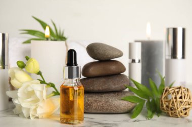 Beyaz mermer masanın üzerinde gerekli yağdan yapılmış bir şişe. Spa ürünü
