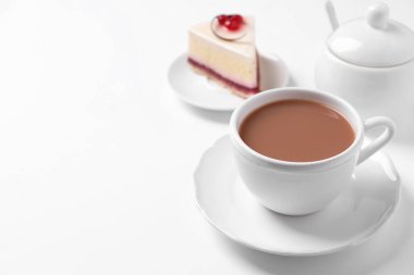 Beyaz arka planda tatlı yanında sütlü çay. Metin için boşluk