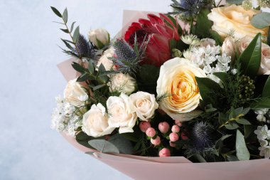 Açık mavi arka planda gülleri olan güzel bir buket, yakın plan.