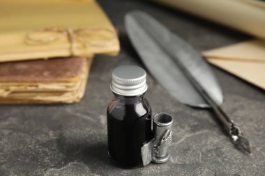 Gri masa üzerinde tüy kalem ve bir şişe mürekkeple kompozisyon