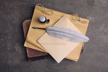 Gri masa üzerinde tüy kalem ve bir şişe mürekkeple kompozisyon, üst manzara.