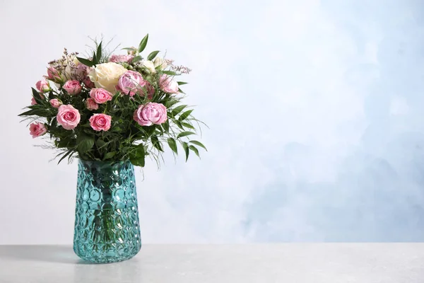 Beautiful bouquet with roses on light table. Space for text