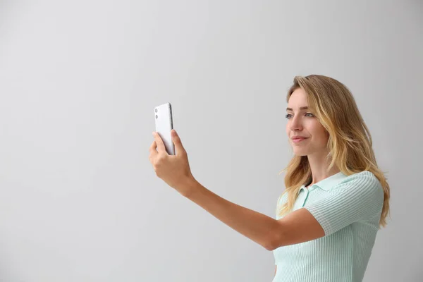 Jovem Mulher Desbloqueando Smartphone Com Scanner Facial Fundo Cinza Verificação — Fotografia de Stock