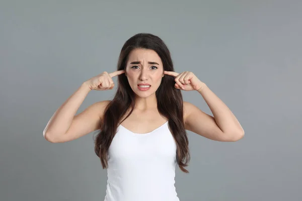 Emotionale Junge Frau Bedeckt Ohren Mit Fingern Auf Grauem Hintergrund — Stockfoto