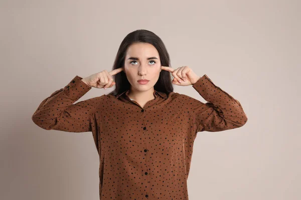 Junge Frau Bedeckt Ohren Mit Fingern Auf Beigem Hintergrund — Stockfoto