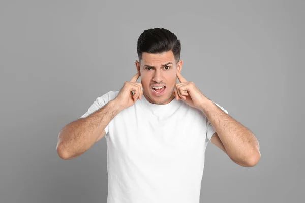 Emotional Man Covering Ears Fingers Grey Background — Stock Photo, Image