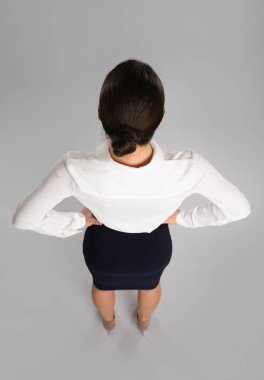 Gri arka planda zarif takım elbiseli genç bir iş kadını.