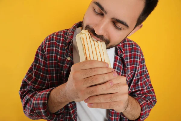 Ung Man Äter Välsmakande Shawarma Gul Bakgrund Närbild — Stockfoto