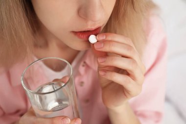 Bulanık arka planda kürtaj hapı alan genç kadın, yakın plan.