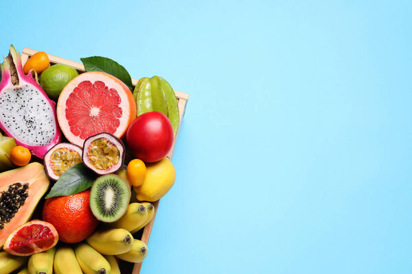 Ящик с различными экзотическими фруктами на голубом фоне, вид сверху. Пространство для текста