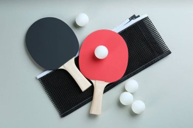 Ping pong raketleri, ağ ve toplar gri arka planda, düz yatıyordu