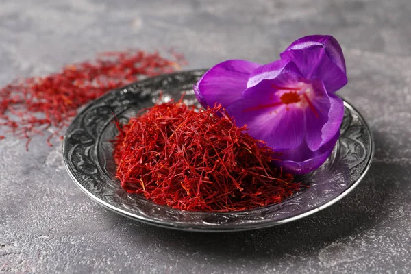 Dried saffron and crocus flower on grey table, closeup