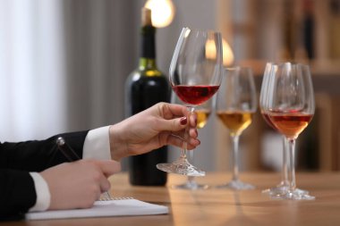 Sommelier içerideki masada farklı türde şarap tadıyor, yakın plan.