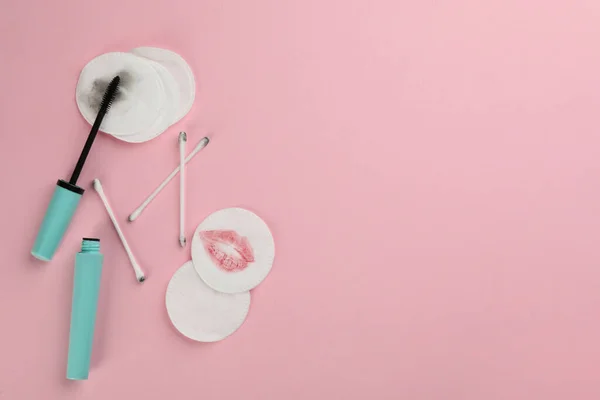 Clean and dirty cotton pads, swabs with mascara on light pink background, flat lay. Space for text