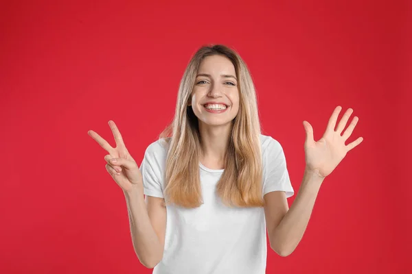 Mujer Mostrando Número Siete Con Sus Manos Sobre Fondo Rojo — Foto de Stock