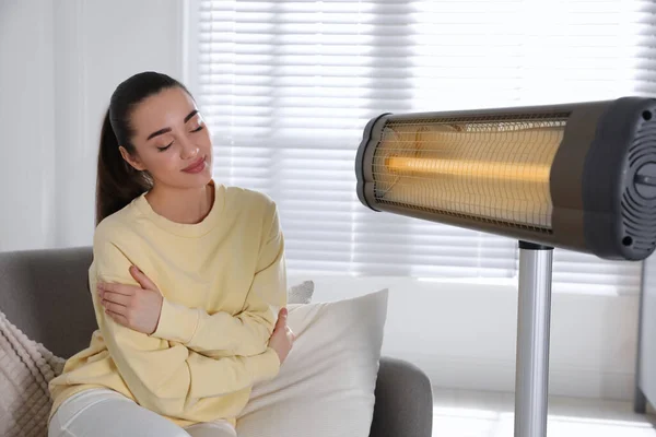 Jovem Mulher Sentada Sofá Perto Aquecedor Elétrico Casa — Fotografia de Stock