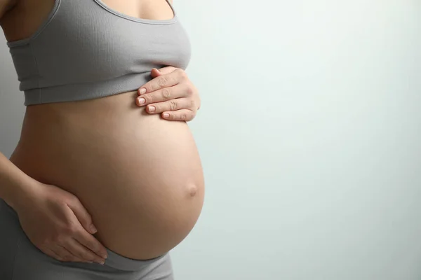 Mulher Jovem Grávida Tocando Barriga Fundo Claro Close Espaço Para — Fotografia de Stock