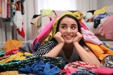 Odada bir sürü elbisesi olan mutlu genç bir kadın. Hızlı moda.