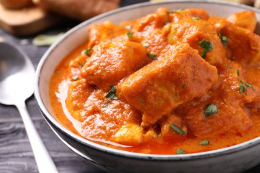 Siyah ahşap masada bir kase lezzetli körili tavuk, yakın plan.