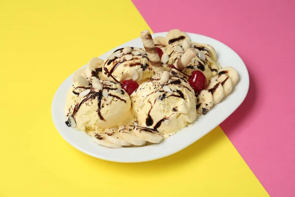 Delicious dessert with banana ice cream on color background