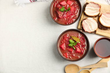 Beyaz masa örtüsü üzerinde servis edilen Ukrayna borsch 'lu kahverengi kil kase düz yerde. Metin için boşluk