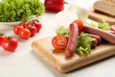 Marul ve domatesli lezzetli vejetaryen sosisleri beyaz ahşap masada.