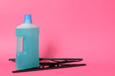 Pembe arka planda bir şişe cam sileceği sıvısı ve sileceği. Metin için boşluk