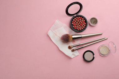Açık pembe arka planda kirli ıslak mendil, fırça ve kozmetik. Metin için boşluk