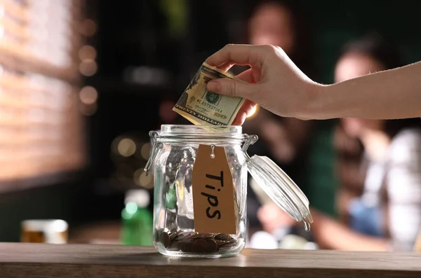 Woman Putting Tips Glass Jar Wooden Table Indoors Closeup — Stock Photo, Image